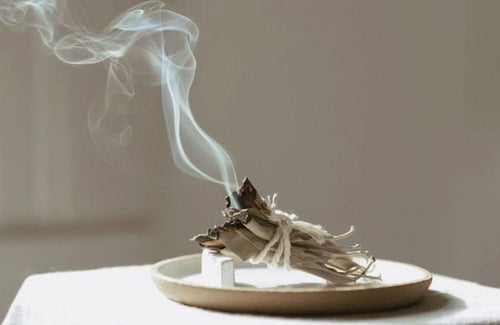 Incense burning on a white plate with smoke rising against a neutral background Toronto energy healing